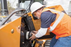 man changing the air filter in a backhoe