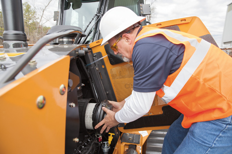 man changing the air filter in a backhoe